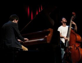 Pianist und Kontrabassist spielen gemeinsam auf einer abgedunkelten Bühne
