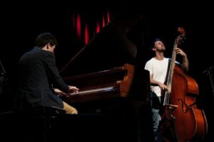 Pianist und Kontrabassist spielen gemeinsam auf einer abgedunkelten Bühne